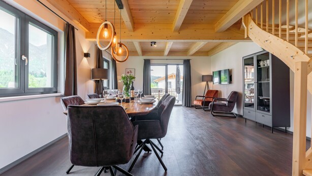 Een ruime eetruimte met een houten plafond, een trap en uitzicht op de omgeving.