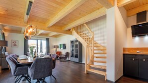 Een modern interieur met een houten trap, een eethoek en een keuken.