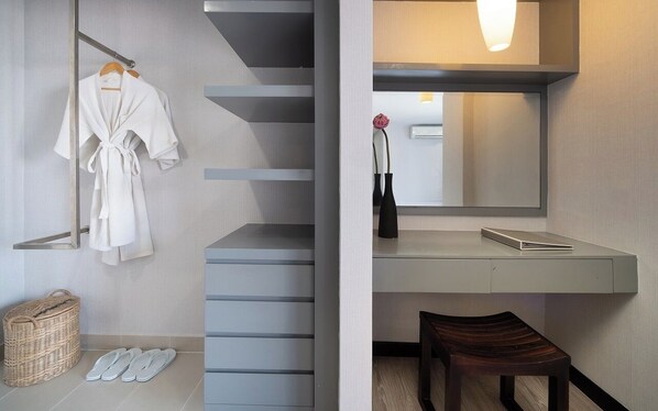 A modern bathroom with a large mirror, a wooden bench, a robe rack, and a wicker basket.