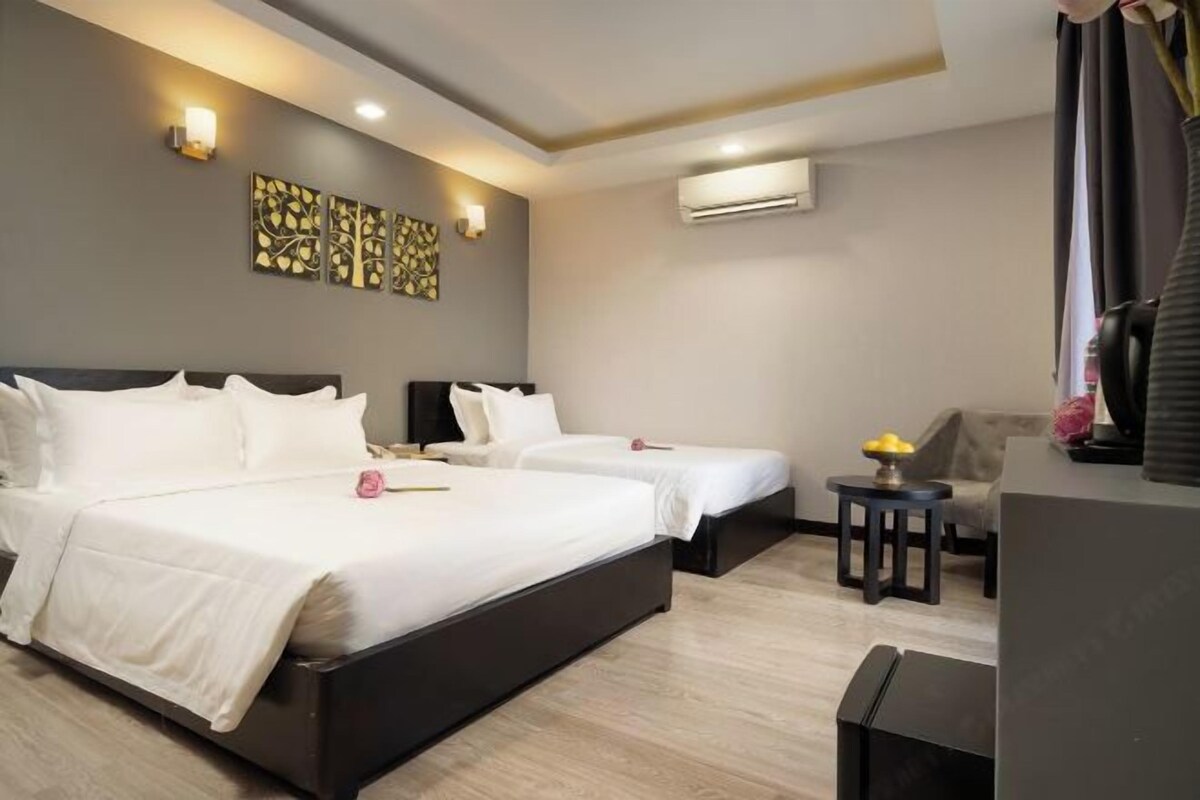Une chambre d’hôtel avec deux lits, un bureau, une chaise et des œuvres d’art accrochées au mur.