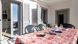 An outdoor dining area with a table set for two, a sliding glass door, and a view of the surrounding area.