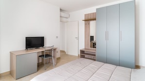 A bedroom with a bed, a desk with a television, a chair, and a wardrobe. - GuestHost - Scaringi Palace - Room 3A (Trani)