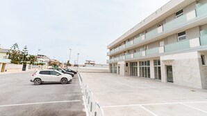 A modern building with a parking lot, multiple floors, and a row of parked cars. - GuestHost - Scaringi Palace - Room 3A (Trani)