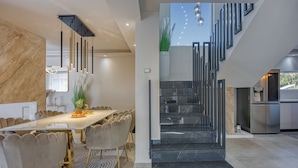 A modern kitchen with a stainless steel refrigerator, a dining area with a marble table and chairs, and a staircase with a black railing. - Villa Samara with Pool (Pula)