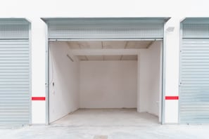 A large, empty industrial-style garage with metal doors and a concrete floor.