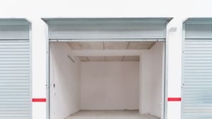 Een ruime, lege garage in industriële stijl, met metalen deuren en een betonnen vloer.
