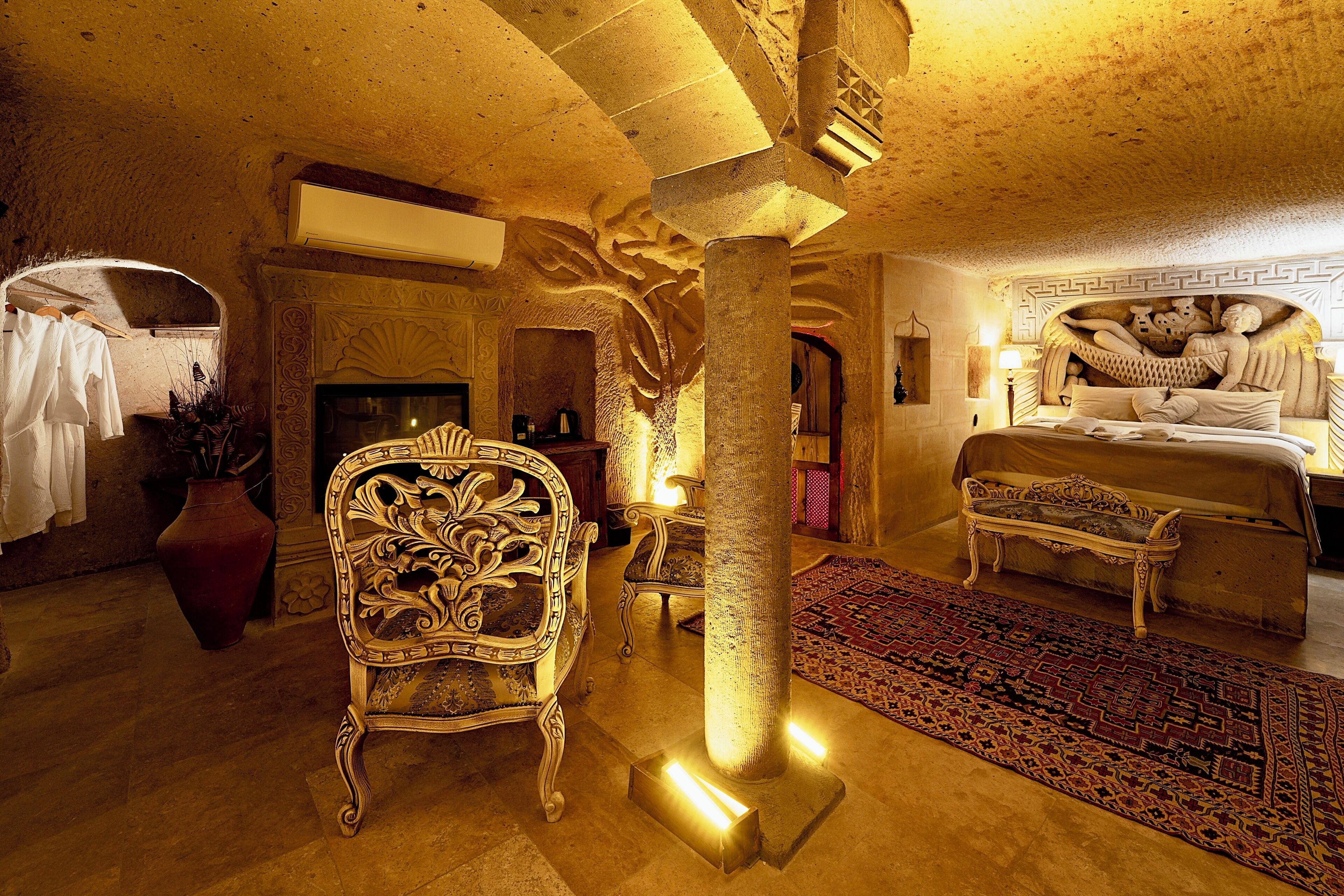 A luxurious room with a large ornate chair, a bed with a unique headboard, and a decorative pillar.