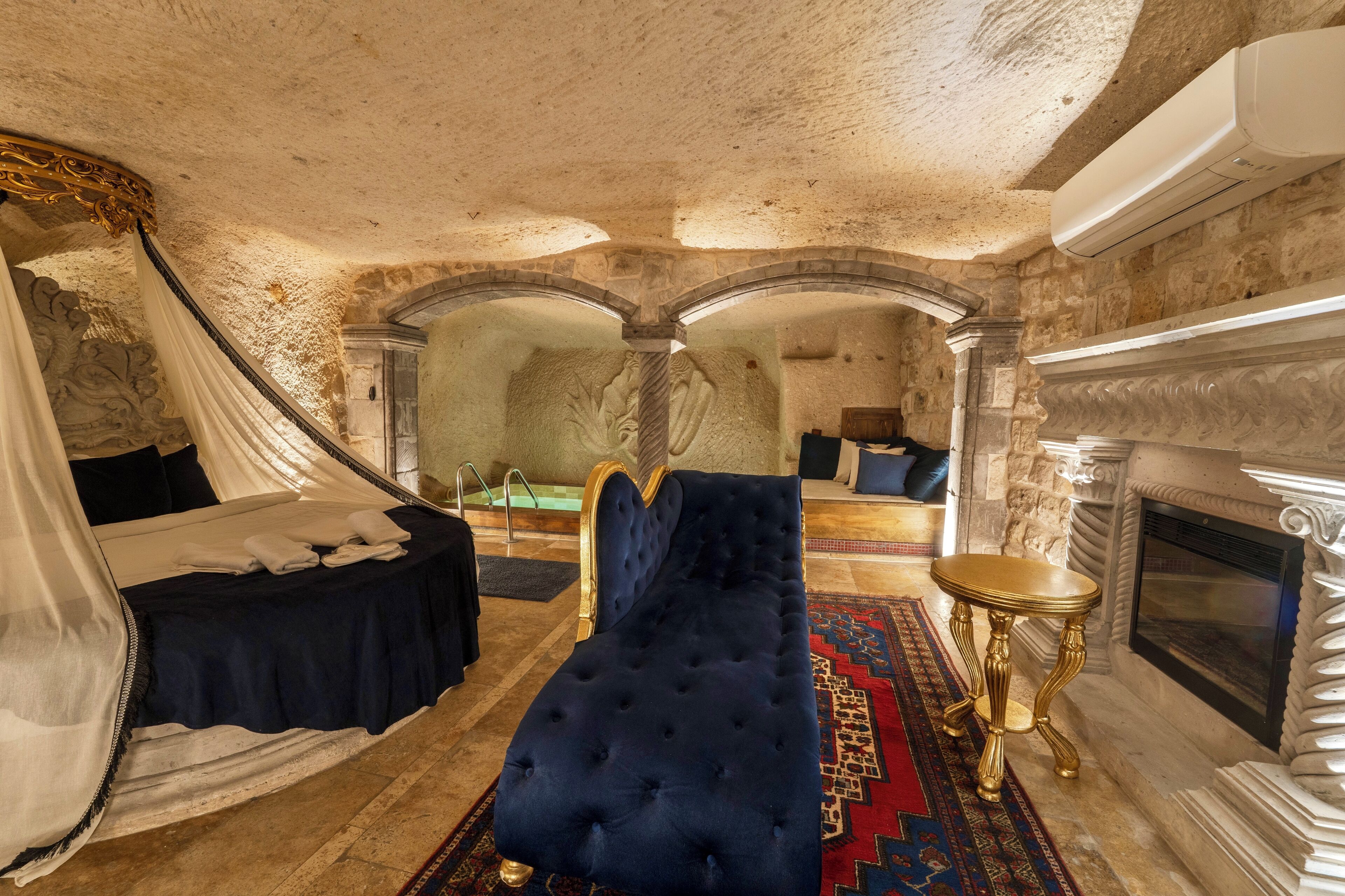 Un dormitorio lujoso con una cama grande, chimenea y pared de piedra.