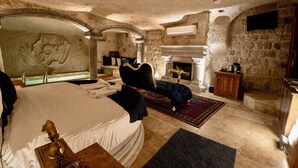 Ein Schlafzimmer mit Steinwänden, einem großen Bett, einem Kamin und einem steinernen Bogen.