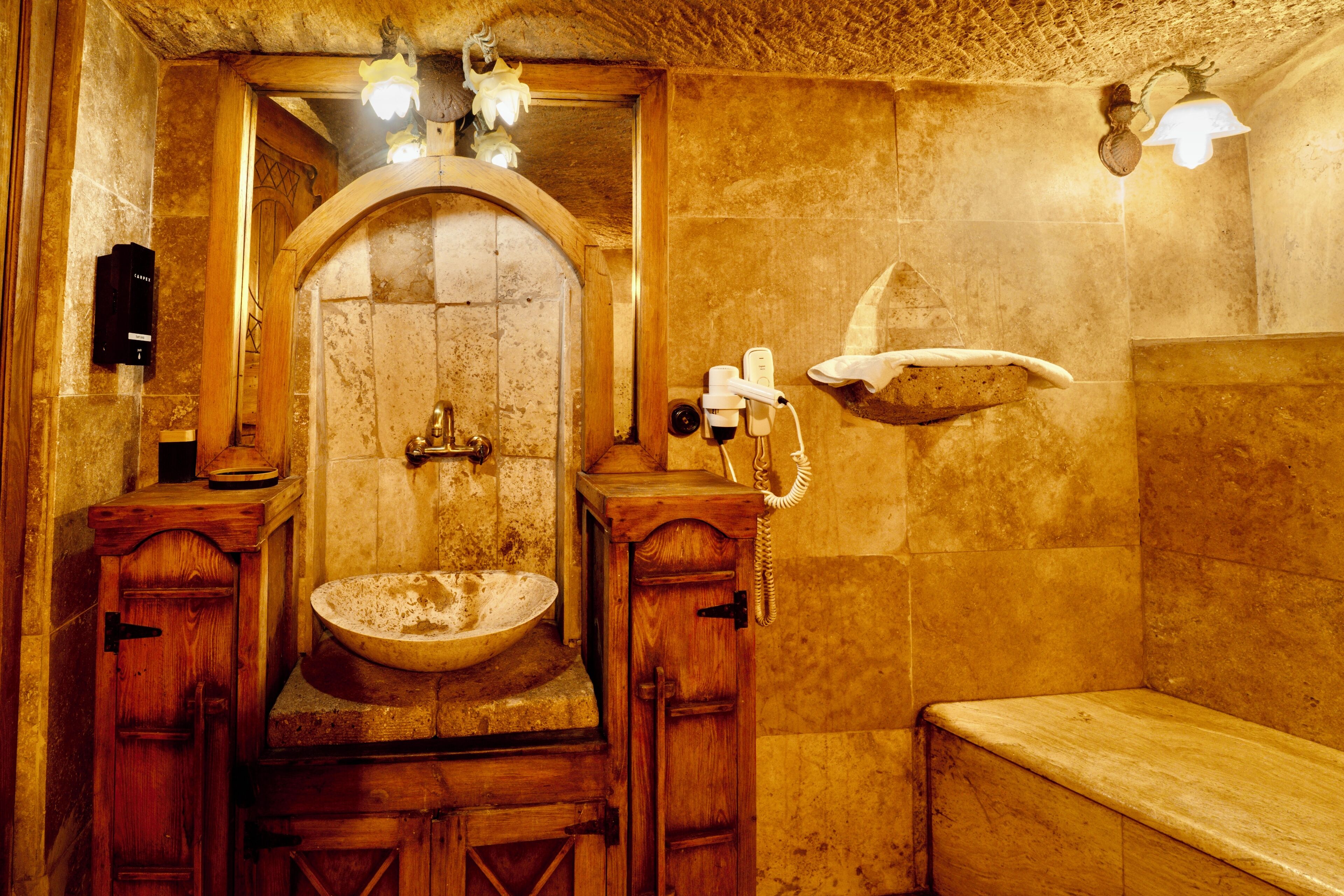Une salle de bain rustique avec un lavabo en pierre, des meubles en bois et un banc.