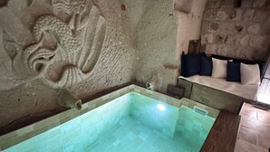 Ein Zimmer mit Steinsäulen, einem gefliesten Pool und einem in den Wand geritzten Drachenmuster.
