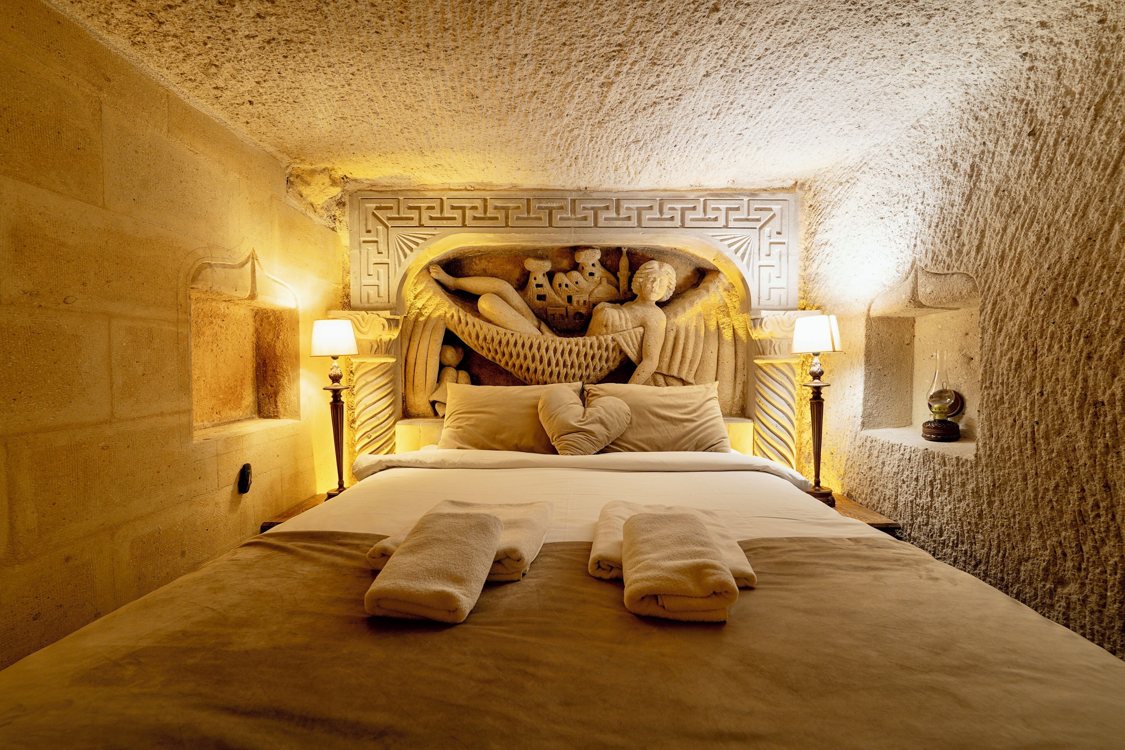 A room with a bed, two bedside lamps, and a decorative headboard.