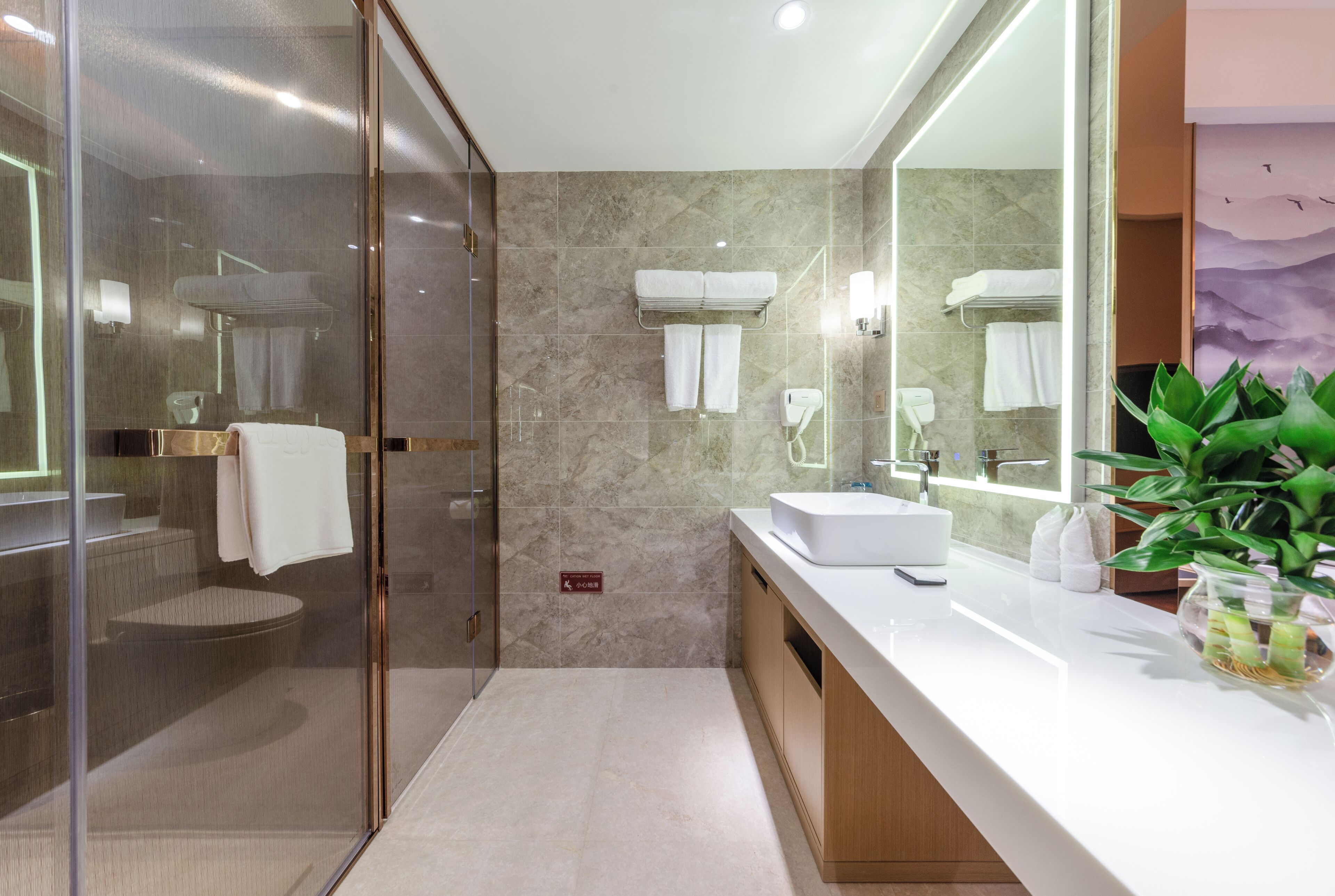 Un baño moderno con ducha acristalada, lavamanos blanco y un espejo grande.