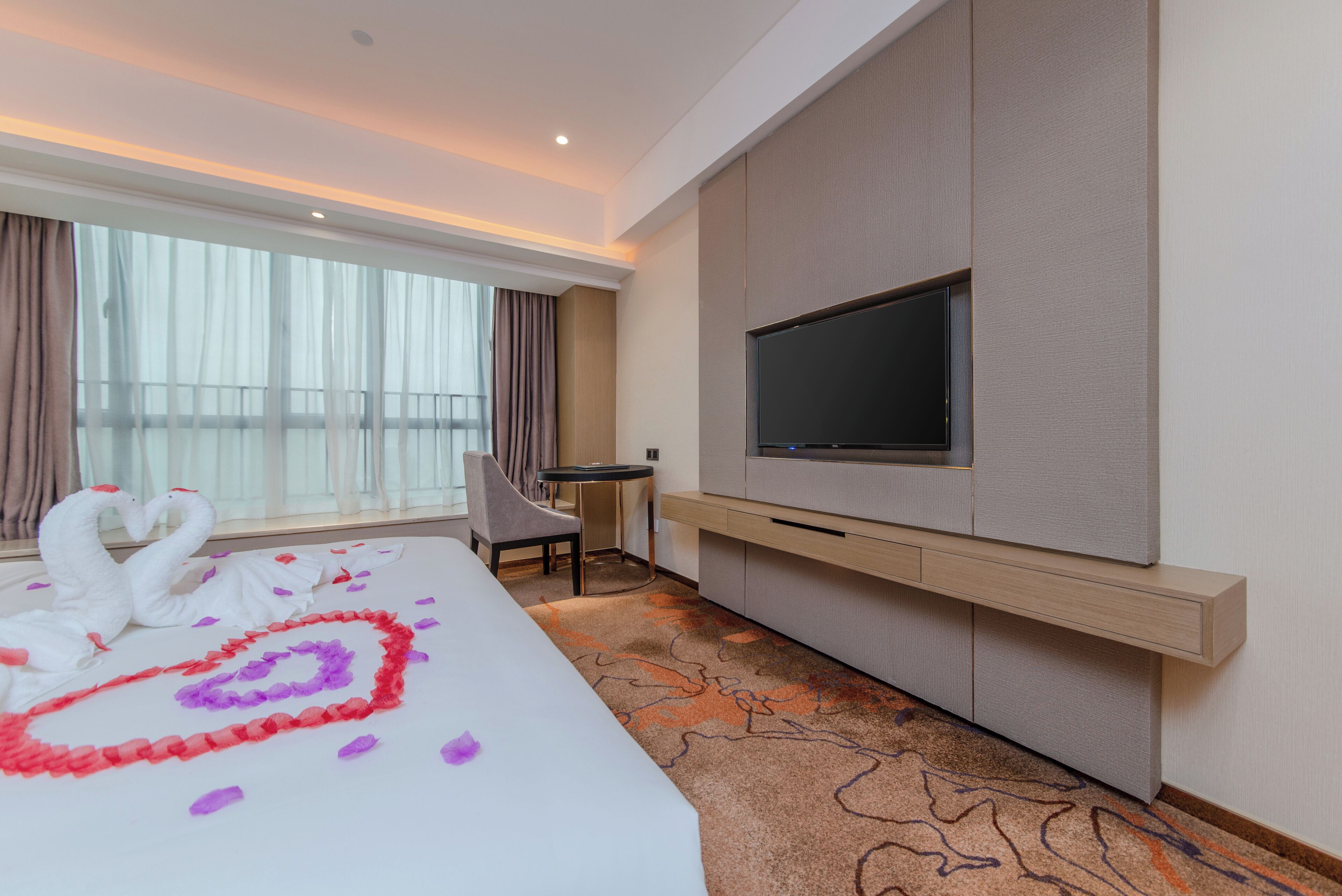 Une chambre d’hôtel avec un grand lit, un téléviseur à écran plat, un bureau et une chaise.