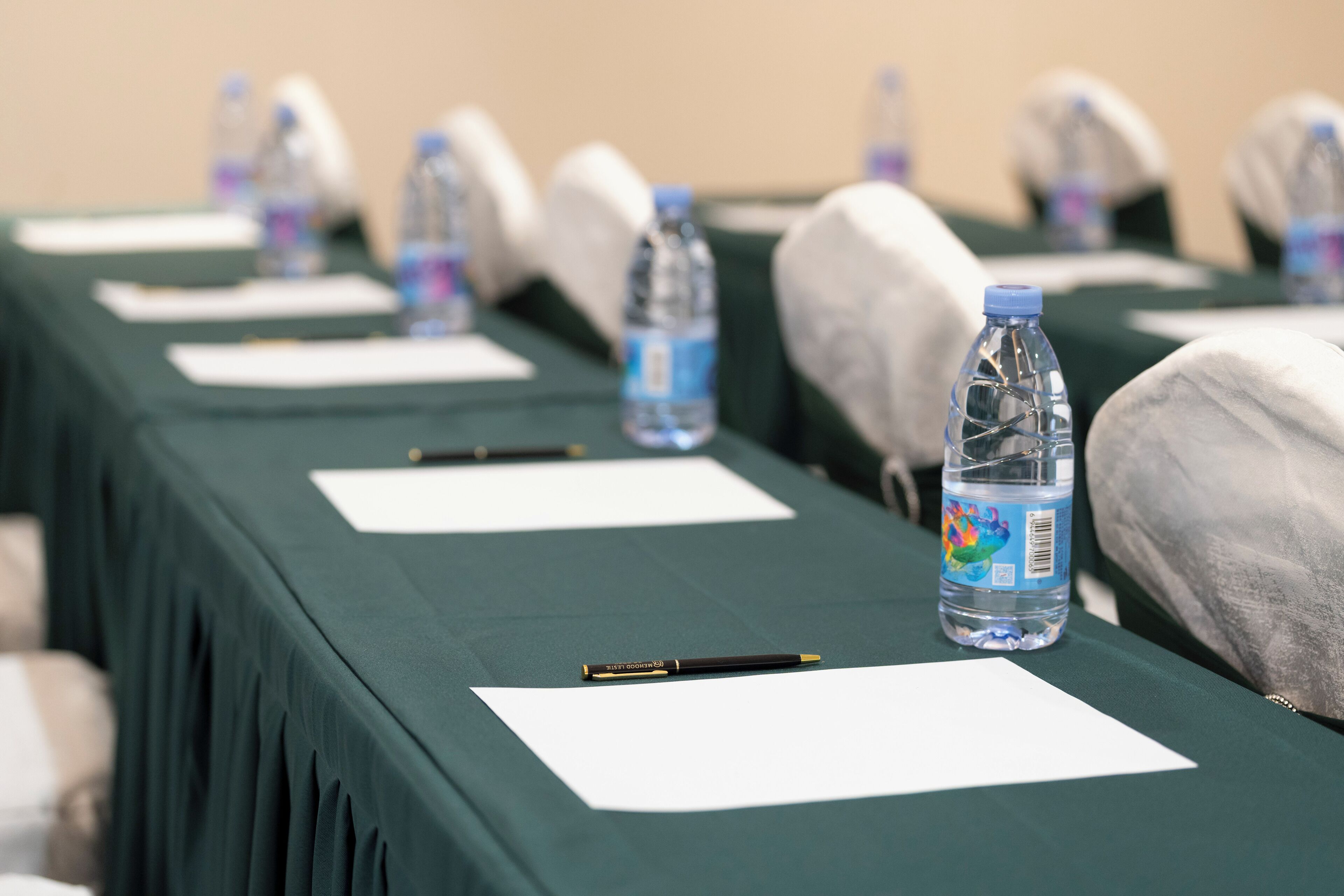 Una mesa de conferencias con botellas de agua, bolígrafos y hojas en blanco.