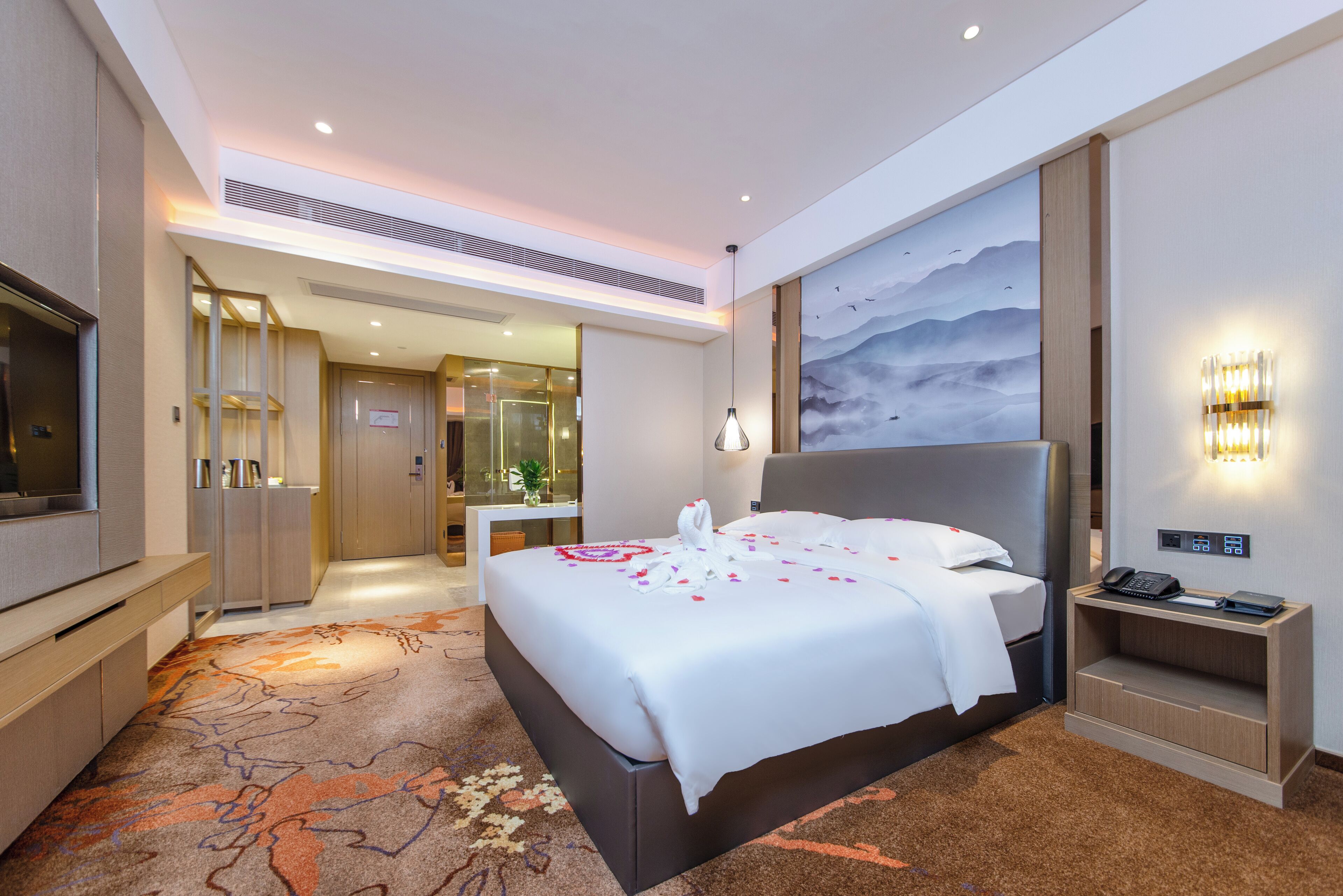 Ein Hotelzimmer mit einem großen Bett, einem Schreibtisch, einem Fernseher und einem Gemälde an der Wand.