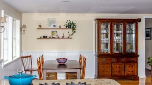 Un comedor con una mesa de madera, sillas, una olla azul y una aparadora.