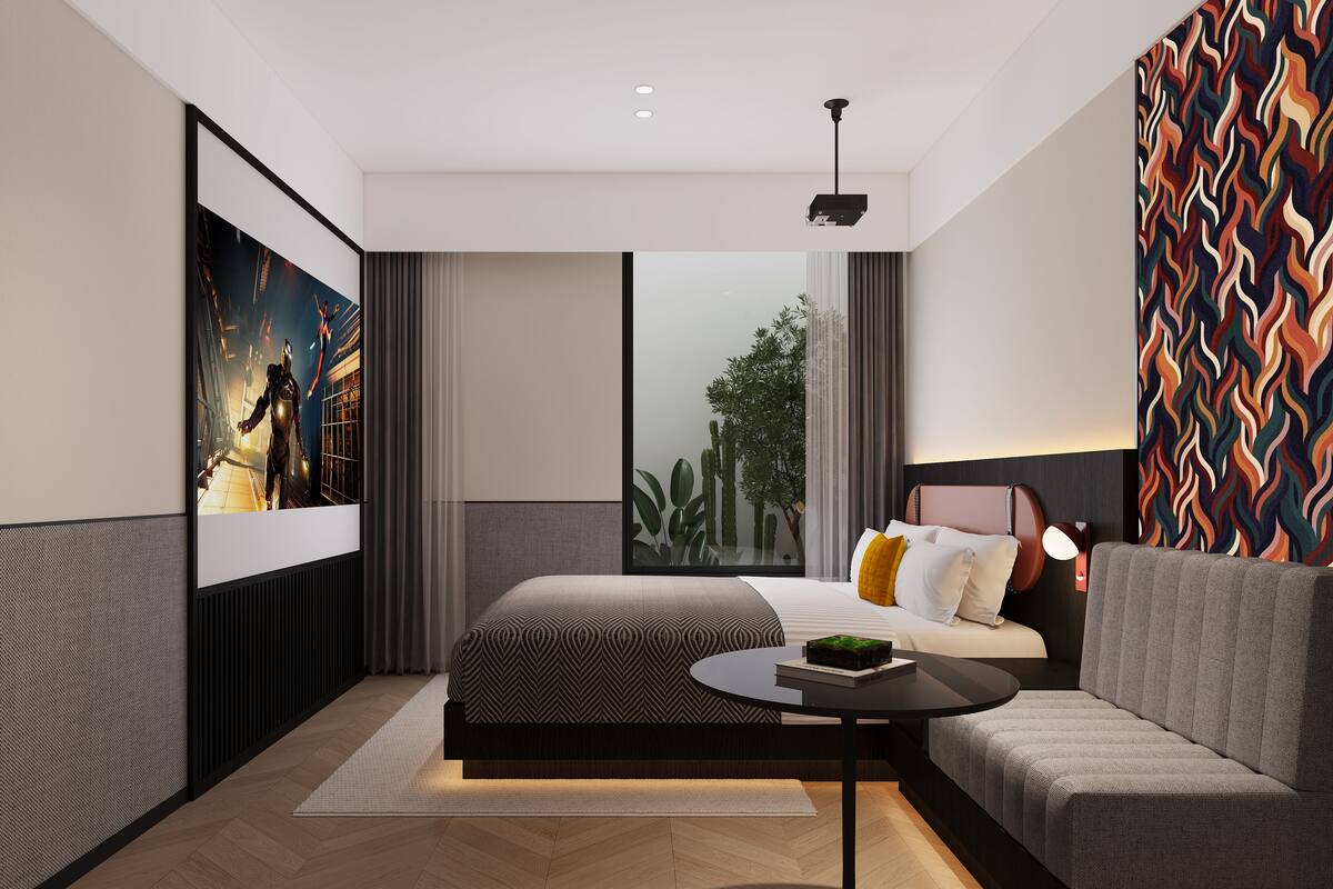 A modern hotel room with a large bed, a sofa, a small table, and a large window offering a view of greenery.