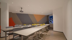 Une salle de conférence équipée d’une longue table, de chaises et d’un projecteur.