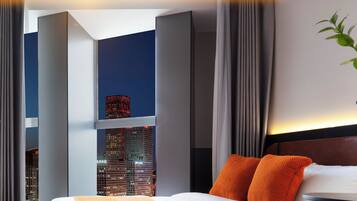 Quarto de hotel moderno com uma cama grande, vista para a cidade e um projetor no teto.