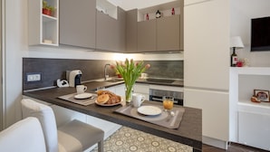 A modern kitchen with a built-in coffee maker, a sink, and a dining area with a chair and a small table. - GuestHost - Lovely apartment for 4 people, located just 200 meters from the sea. The accommodation boasts every comfort e a palette of warm colors that create a welcoming and cheerful environment. Ideal location: just 5 minutes walk from Corso Vittorio E (Bari)