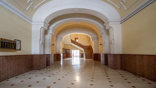 A spacious hallway with a marble floor, white walls, and a central staircase leading to an upper level. - GuestHost - Lovely apartment for 4 people, located just 200 meters from the sea. The accommodation boasts every comfort e a palette of warm colors that create a welcoming and cheerful environment. Ideal location: just 5 minutes walk from Corso Vittorio E (Bari)