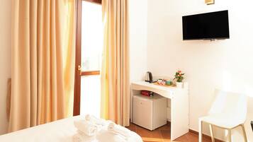 Habitació d'hotel amb llit, escriptori amb televisió, cadira i nevera petita.