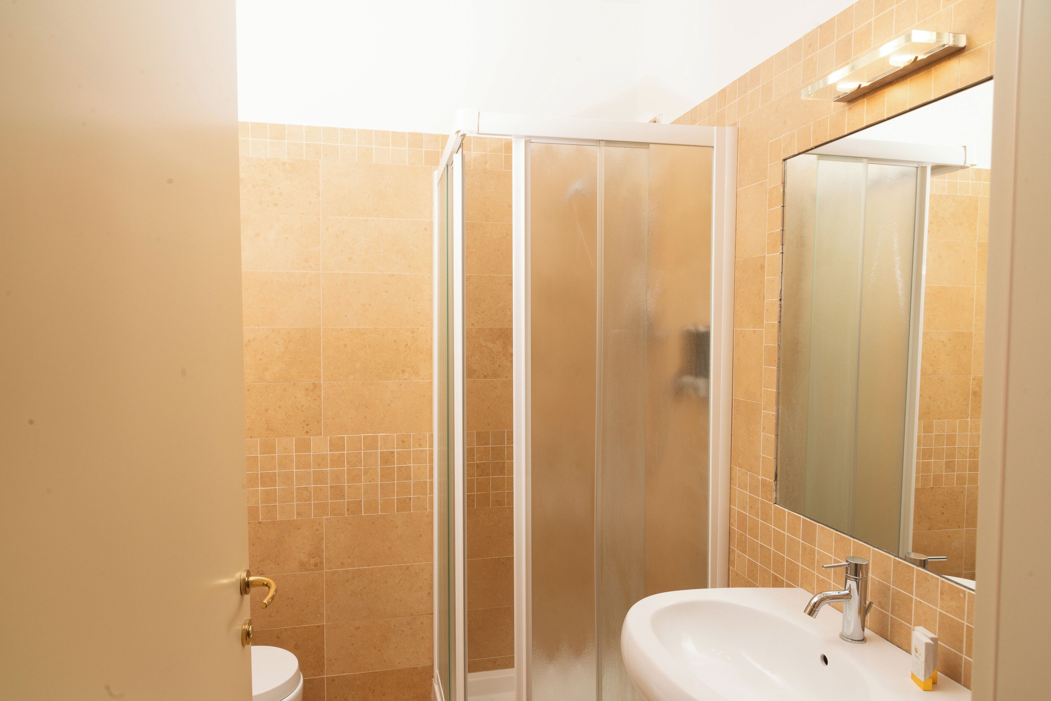 Ein Badezimmer mit Duschkabine, Waschbecken und Spiegel.
