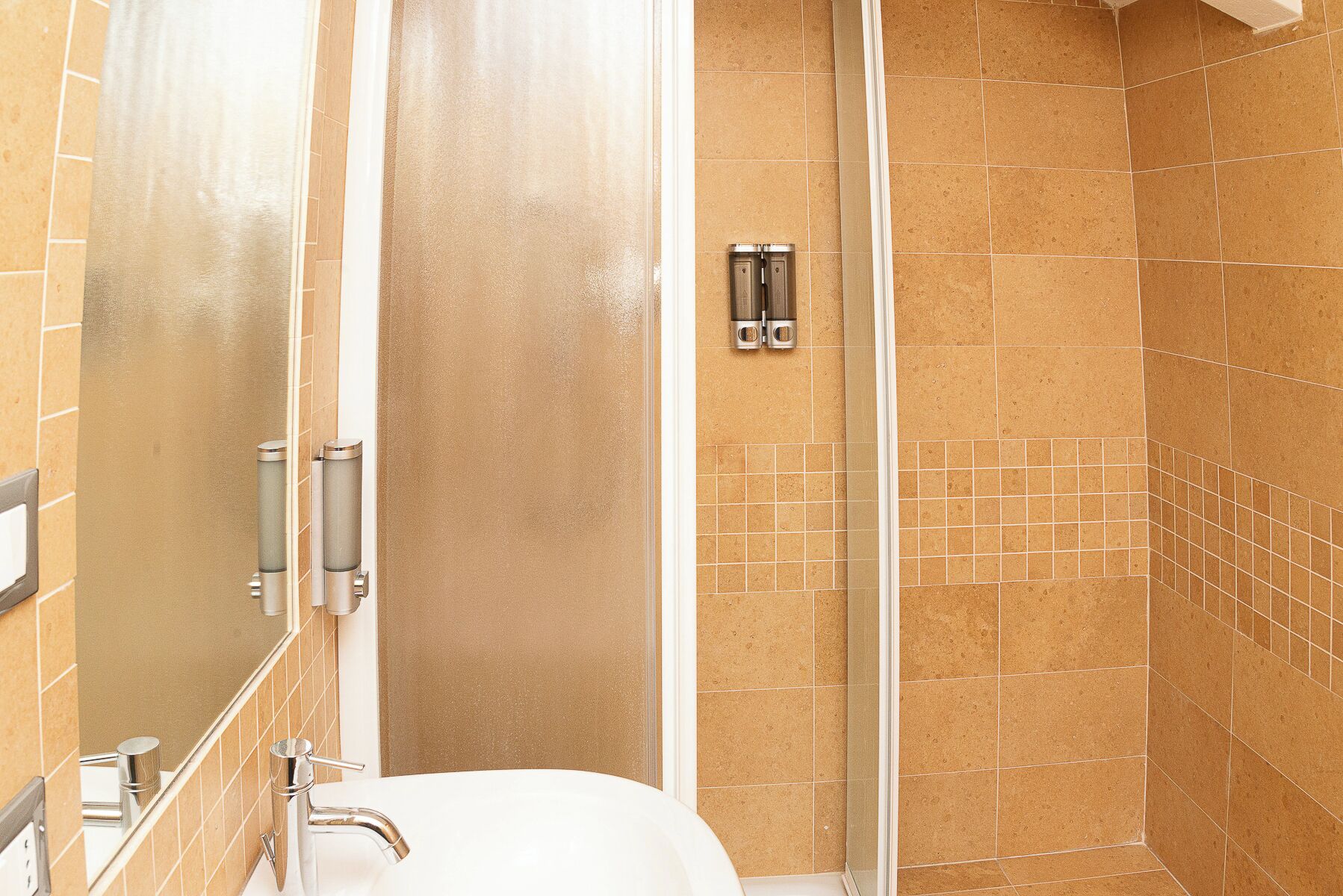 A bathroom with a shower, a sink, and a mirror.