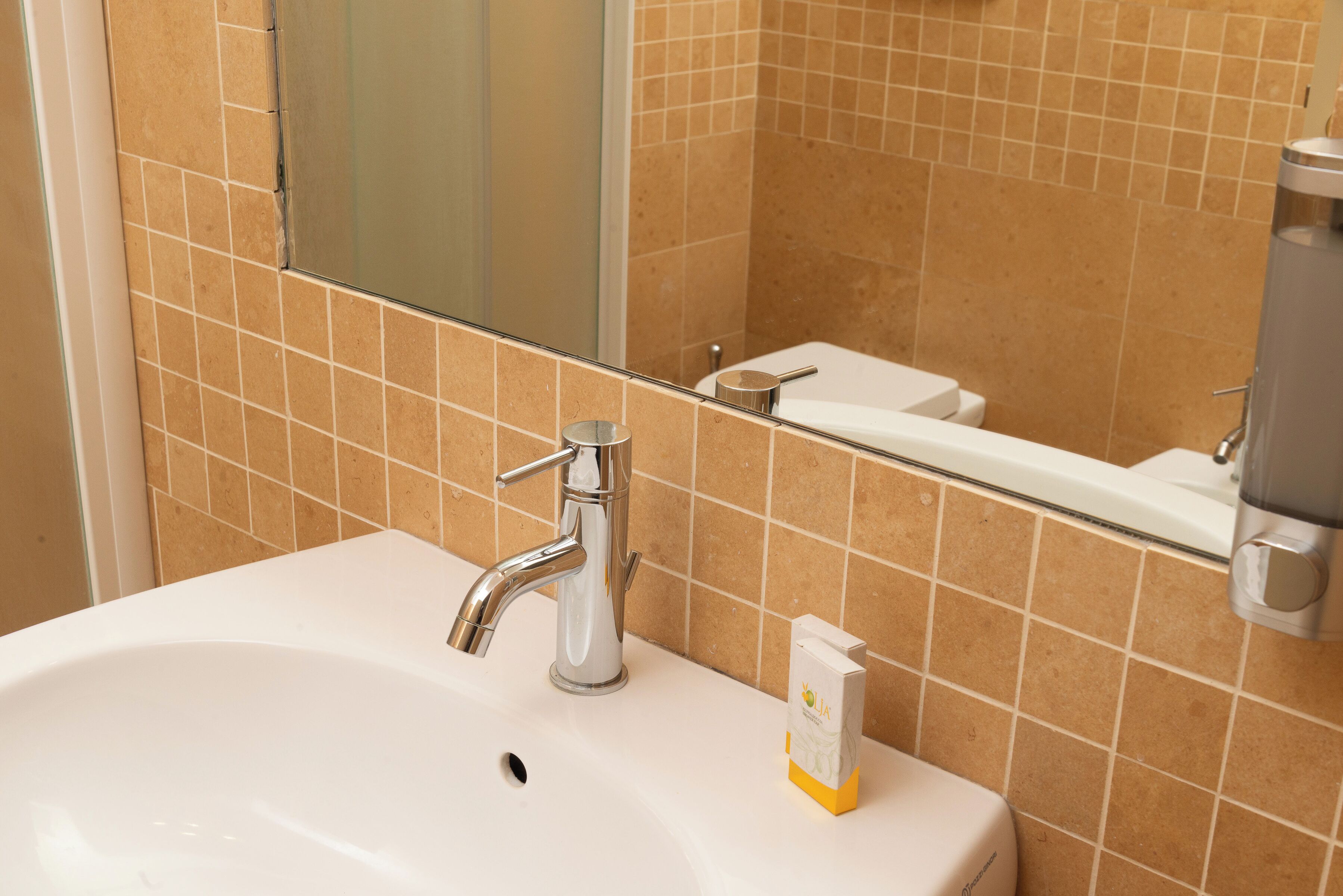Un bagno con un lavandino bianco, uno specchio e un water.