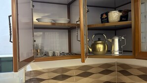 A kitchen with a built-in stove, a sink, and a cabinet with shelves. - Luluat Althuraya Serviced Apartments (Riyadh)