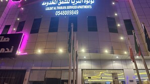 A building with a sign for Loloat Al Thuraya Service Apartments, featuring a modern design with illuminated neon lights. - Luluat Althuraya Serviced Apartments (Riyadh)