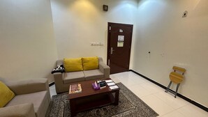 A living room with a sofa, a coffee table, and a door. - Luluat Althuraya Serviced Apartments (Riyadh)