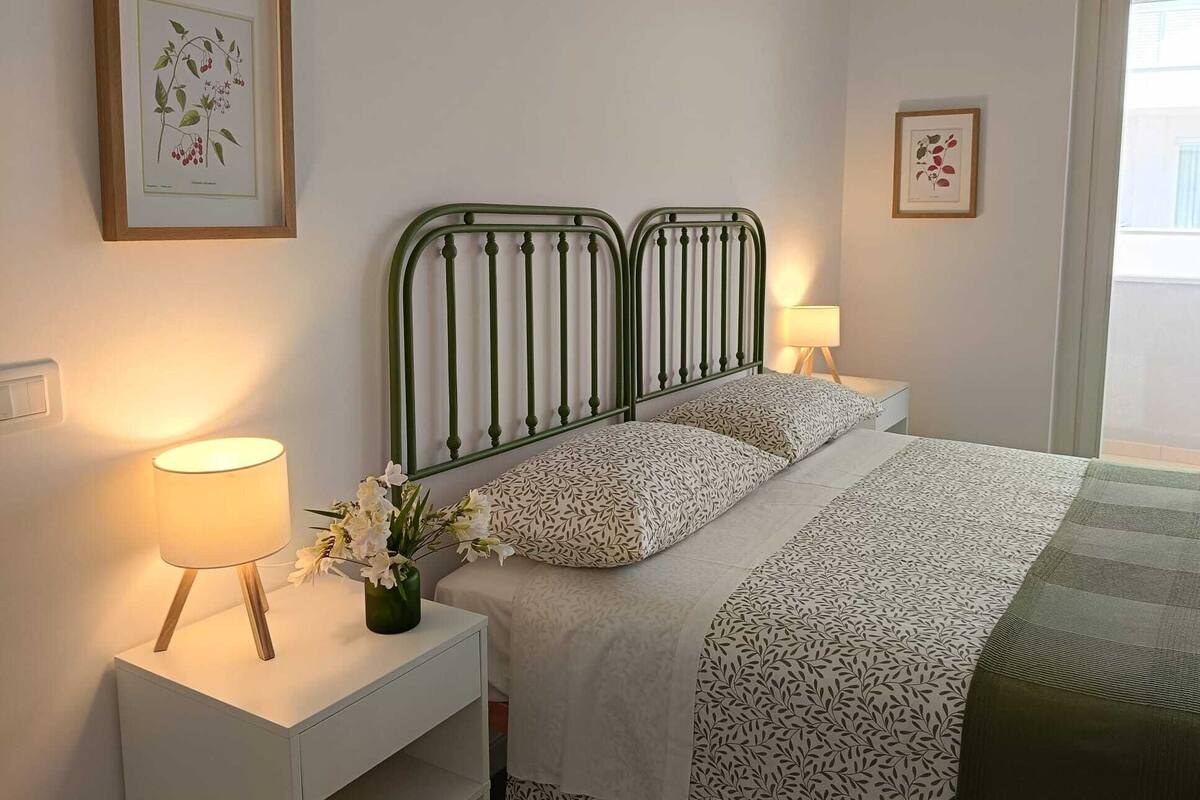 A bedroom with a bed, bedside tables, and wall-mounted artwork.