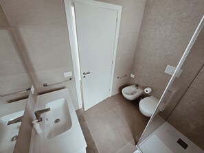 A bathroom with a sink, bidet, toilet, and a door.