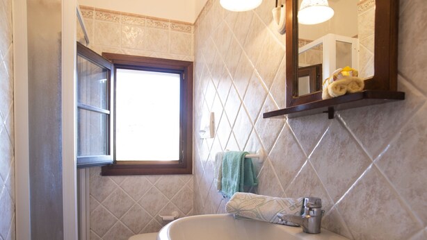 Un baño con un lavabo blanco, un inodoro y una ventana.