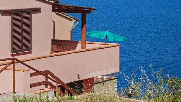 Ein Küstengebäude mit einem Balkon mit Blick auf das Meer.