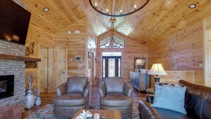 A cozy log cabin interior with a fireplace, leather armchairs, a sofa, and a dining table. - Majestic Mountain Views: Sevierville Escape! (Sevierville)