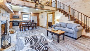 A spacious living area with a sofa, coffee table, and a zebra rug. A staircase with a railing leads to an upper level. - Pet-Friendly Yard! Nature Escape in Forest City (Forest City)