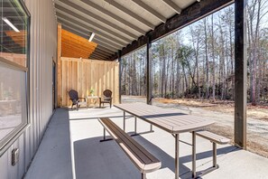 A covered outdoor area with a picnic table and chairs, a wooden deck, and a view of a forest. - Pet-Friendly Yard! Nature Escape in Forest City (Forest City)