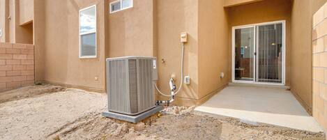 An air conditioning unit mounted on a building exterior, a small window, and a sliding glass door.