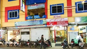 Un immeuble à plusieurs étages, avec une enseigne indiquant la présence d’un hôtel et divers commerces au rez-de-chaussée.