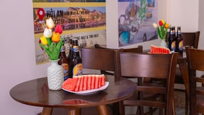 A table with a vase of tulips, beer bottles, and watermelon slices. - BOO BEACH Hostel, 24-Hour Reception & Free Billiards (Da Nang)