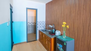 A compact kitchen with wooden cabinets, a built-in refrigerator, and a tiled backsplash. - BOO BEACH Hostel, 24-Hour Reception & Free Billiards (Da Nang)