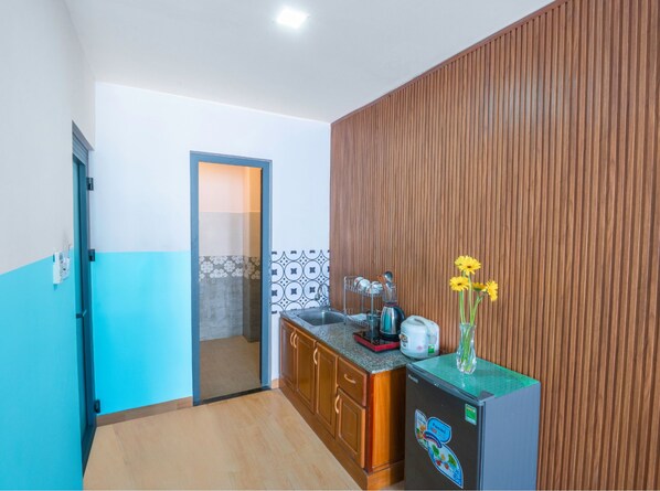 A compact kitchen with wooden cabinets, a built-in refrigerator, and a tiled backsplash. - BOO BEACH Hostel, 24-Hour Reception & Free Billiards (Da Nang)