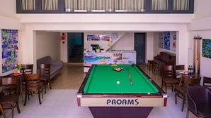 A pool table in a room with a reception desk, chairs, and a piano. - BOO BEACH Hostel, 24-Hour Reception & Free Billiards (Da Nang)