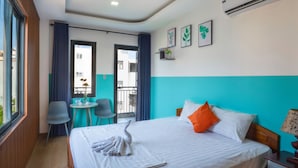 A hotel room with a bed, a desk, and a chair. There is a window, a door, and an air conditioning unit on the wall. - BOO BEACH Hostel, 24-Hour Reception & Free Billiards (Da Nang)