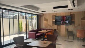 Un interior moderno con una zona de estar, un televisor de pantalla plana en la pared y grandes ventanales que ofrecen vistas al exterior.