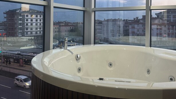 Un baño moderno con una bañera grande, ventanas amplias y vistas a la ciudad.