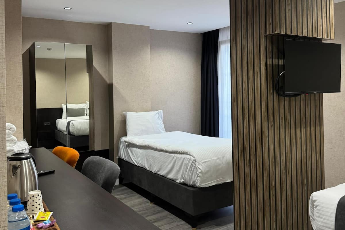 A modern hotel room with a bed, a desk, a flat-screen TV, and a mirror.